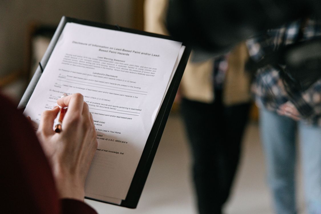 A Filipino couple reviewing housing loan documents at a bank or Pag-IBIG office, comparing options for a house and lot versus a condo purchase