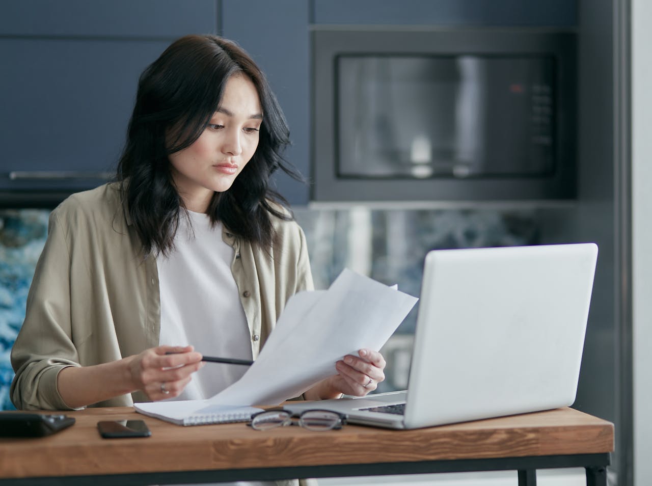 A buyer reviewing developer documents and doing research on a laptop before purchasing a condo