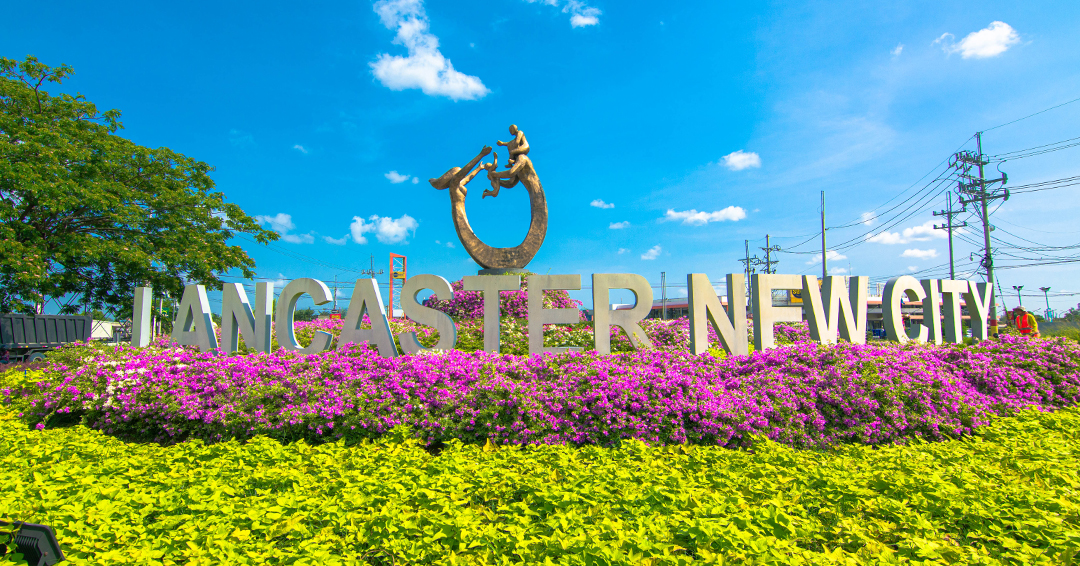 Lancaster New City entrance sign with colorful flowers and blue sky — the gateway to Cavite's largest master-planned community in Imus