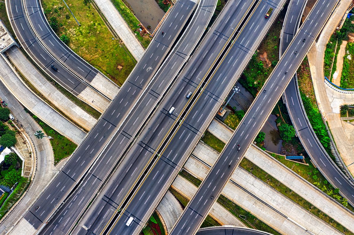Aerial view of an expressway interchange connecting suburban communities to the metro, similar to the CAVITEX and CALAX corridors serving Imus