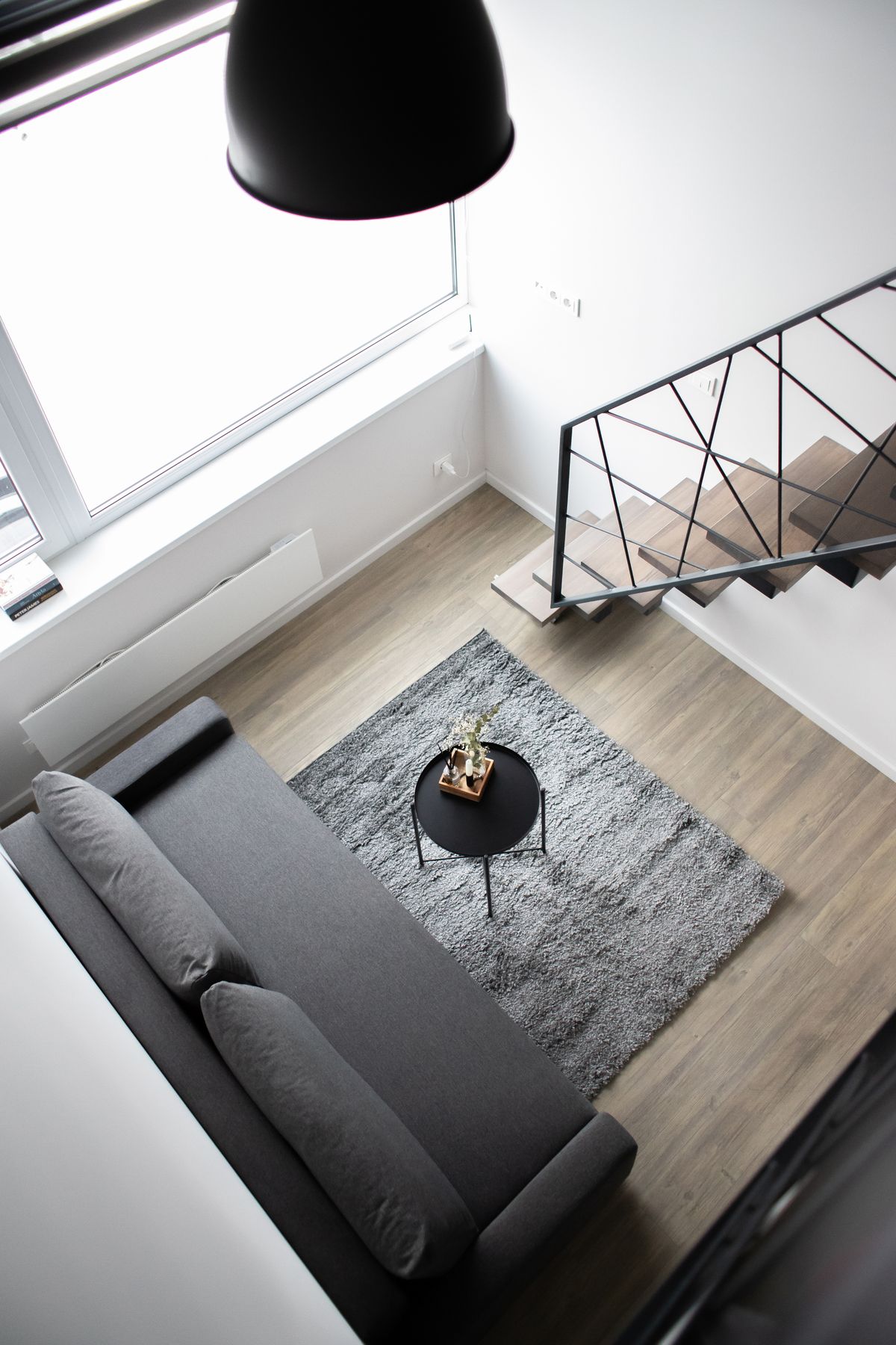 Compact but well-lit studio condo interior in the Philippines showing an open-plan living and sleeping layout with a loft level above